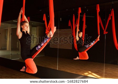 Beautiful young woman, yoga instructor practicing fly yoga in the gym.