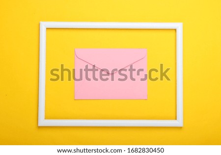 Envelope in a white frame on a yellow background. Top view. Flat lay