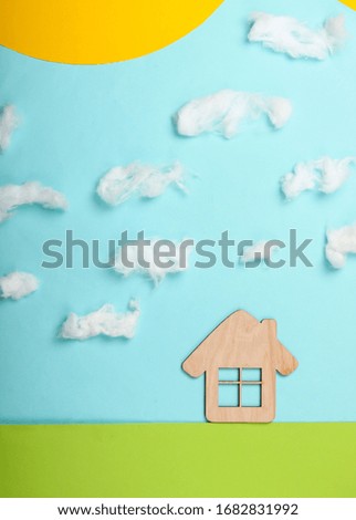 Handmade composition of a house on the lawn and sunny sky with clouds