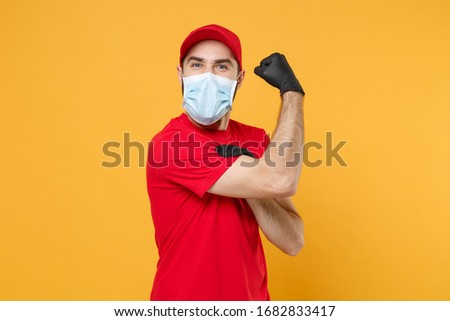 Delivery man in red cap blank t-shirt uniform sterile face mask gloves isolated on yellow background studio Guy employee working courier Service quarantine pandemic coronavirus virus concept