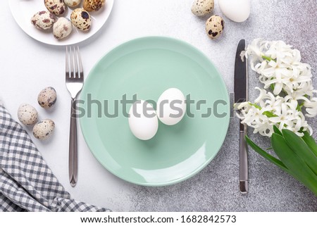 Spring table setting. Green mint plate, easter eggs, hyacinth and silver cutlery on stone background. Copy space. Top view - Image
