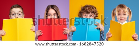 Set of clever girls and boys in glasses covering faces with colorful books and looking at camera with interest against vivid background in studio