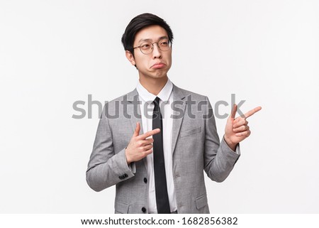 Waist-up portrait of pleased and impressed handsome asian businessman nod in approval and agreement, amazed with employee good project, looking and pointing fingers right, white background