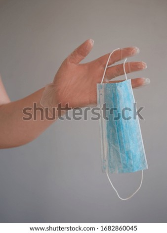 Female hand holds blue surgical mask with rubber ear straps. Typical three-layer surgical mask for covering the mouth and nose. (Clipping path). Protection concept from corona virus
