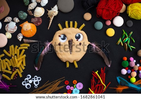 children artwork owl picture made with modeling clay and other art and craft materials on black background