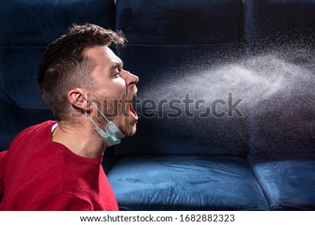 man coughs. Influenza, colds, coronavirus. Infection through an airborne droplet. A guy in a red sweater and a medical mask is coughing. Royalty-Free Stock Photo #1682882323