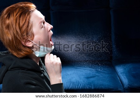 Influenza, cold, coronavirus. Infection through an airborne droplet. Girl with red hair in a medical mask coughs. A cloud of virus droplets in the air. Royalty-Free Stock Photo #1682886874