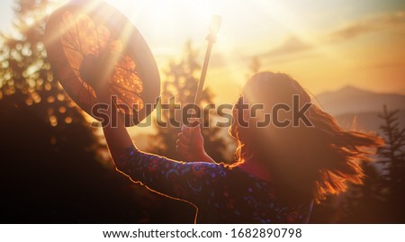 beautiful shamanic girl playing on shaman frame drum in the nature. Royalty-Free Stock Photo #1682890798