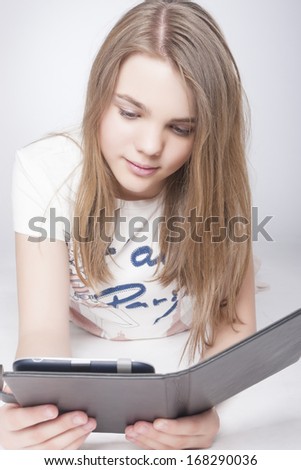 Little Teenage Caucasian Girl With Tablet PC at Home Indoors. Vertical Image. Isolated Over Gray Background