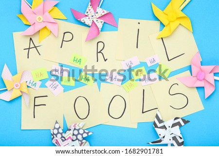 Text April Fool's Day with paper windmills on blue background