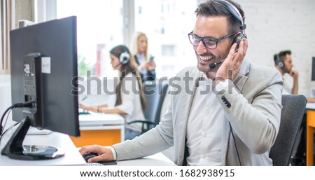 Confident male customer support operator with headset working in call center Royalty-Free Stock Photo #1682938915