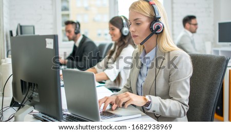 Female telephone worker in headset working on laptop in office Royalty-Free Stock Photo #1682938969