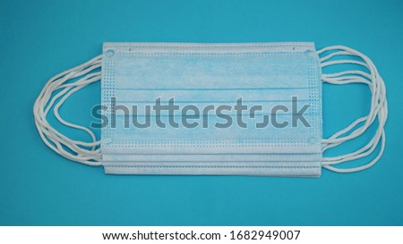 Several medical masks are stacked on a blue background. Surgical mask with rubber ear straps. Typical three-layer surgical mask for covering the mouth and nose. Bacteria mask procedure. Protection con