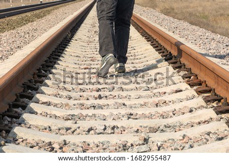 Rails close up. A railway that does not transport people, legs and shoes into the distance. The concept of not driving a train, a closed connection between countries, going far