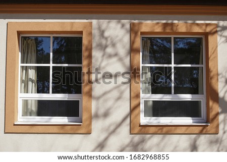 Old double window with wooden shadow on side of house