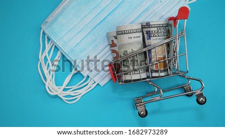 Basket with banknotes on the background of surgical masks on a blue background. Typical three-layer surgical mask for covering the mouth and nose. Mask cost concept. American dollar.