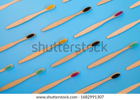 Eco bamboo toothbrushes with multicolored bright bristles on blue background