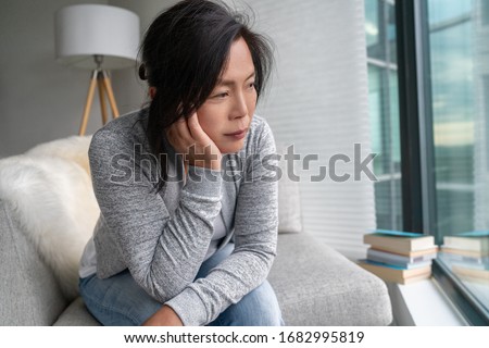 Sad Asian mature woman lonely at home self isolation quarantine for COVID-19 Coronavirus social distancing prevention. Mental health, anxiety depressed thinking senior chinese lady. Royalty-Free Stock Photo #1682995819