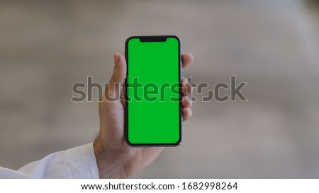 Man wearing a thawb holding a smartphone (green screen)
