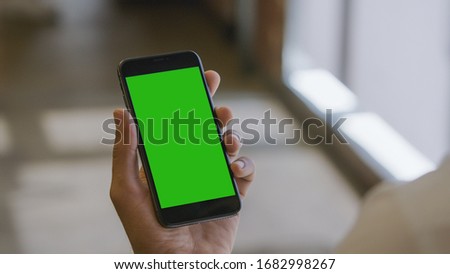 Man holding a smartphone (green screen)