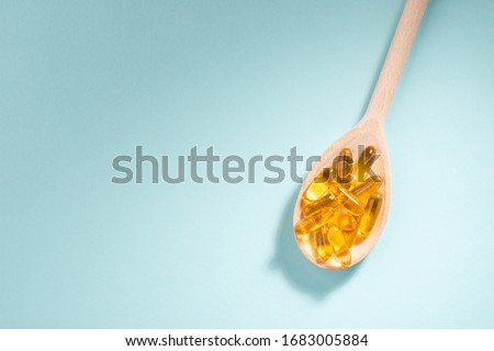 Wooden spoon of Omega-3 capsules on blue background with copyspace. Healthcare, wellbeing and supplements. Royalty-Free Stock Photo #1683005884
