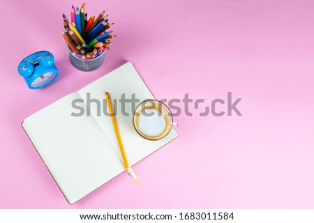 Pencils, note book and clock on the pink table. business conceptual. Top views with clear space