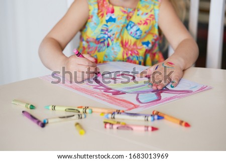 Childrens creativity. Little child girl draws with wax pencils at home. The concept of distance learning online for the period of global quarantine.