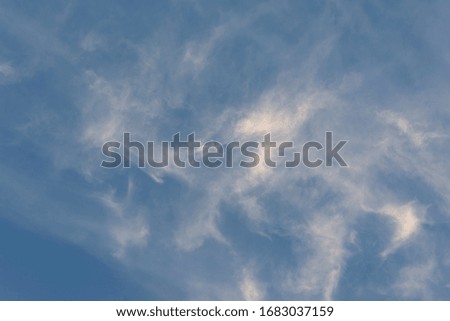 White wispy clouds across a medium blue sky