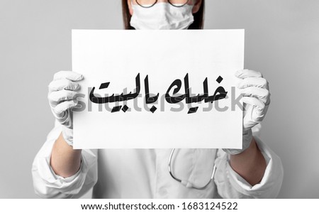#StayAtHome. Woman in protective mask holding Stay at home in arabic inscription, warning of coronavirus quarantine, Covid-19 epidemic, preventive measures for spread of infectious disease. Royalty-Free Stock Photo #1683124522