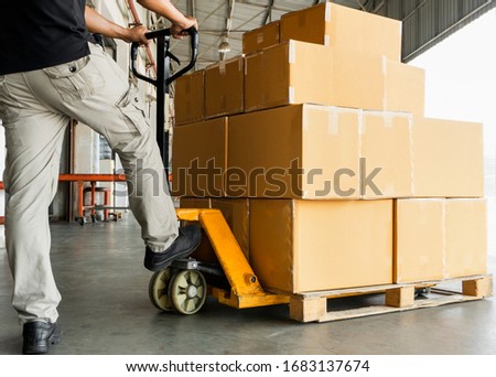 Worker courier unloading shipment goods, hand pallet truck and stack package boxes on pallet. Supply chain warehouse delivery service transport and logistics. Royalty-Free Stock Photo #1683137674