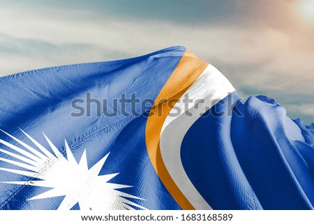 Marshall Islands national flag cloth fabric waving on beautiful sky.