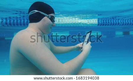 The guy is reading an electronic book underwater. This is a special waterproof electronic device. You can read the text and show signs directly underwater.