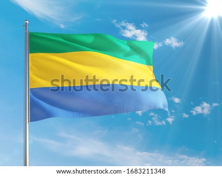Gabon national flag waving in the wind against deep blue sky. High quality fabric. International relations concept.