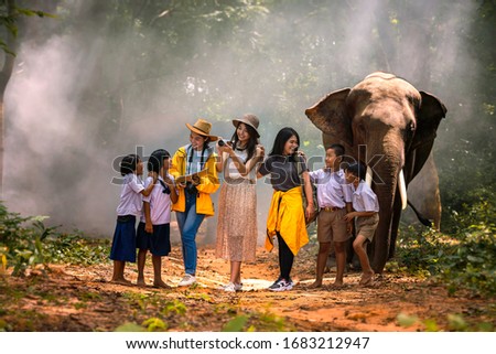 Japanese tourists and Thai tour guides are watching elephants in the jungle. Lost tourist asking for help from a local people in the forest. Royalty-Free Stock Photo #1683212947