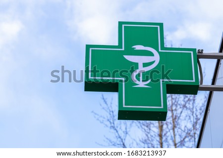 Urban pharmacy or drug store sign, cross green sign of pharmaceutical drugstore, led display green cross on the wall in the city street, copy space.