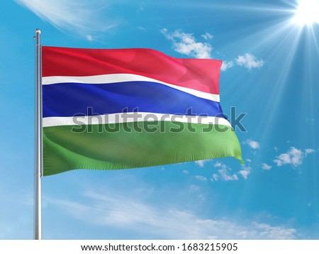 Gambia national flag waving in the wind against deep blue sky. High quality fabric. International relations concept.