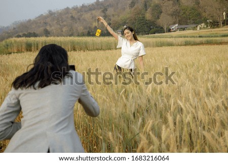 two young thai tourist taking pictures in the barley rice fields farmland in Thailand