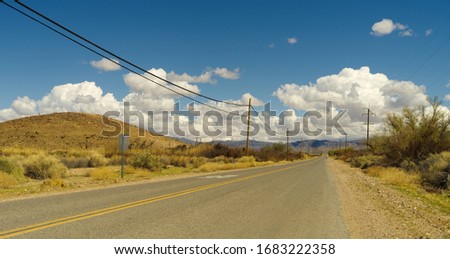 Old Spanish Trail Highway, looking east, near Tecopa in Inyo county. Image taken during a bright afternoon with white puffy clouds in the background.