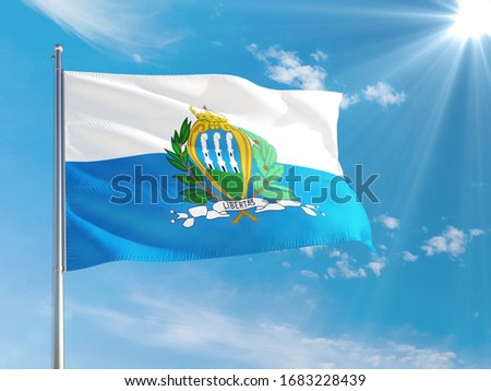 San Marino national flag waving in the wind against deep blue sky. High quality fabric. International relations concept.