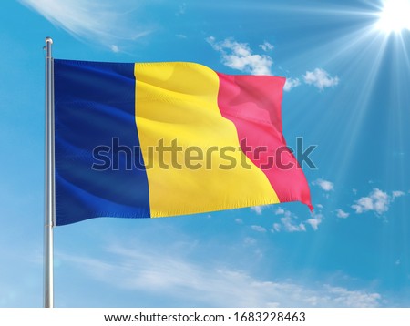 Romania national flag waving in the wind against deep blue sky. High quality fabric. International relations concept.