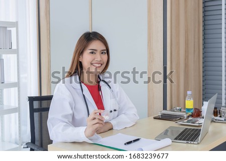 Young Asian doctor working on her desk, holding medicine, hospital and healthcare concept.