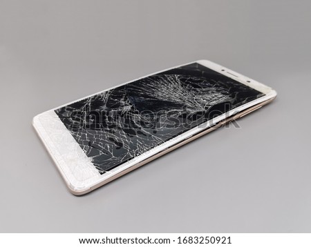 broken white mobile phone, screen crack on grey background