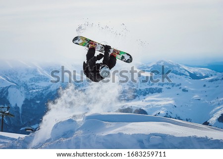 
Snowboarder jumps and does a trick in the mountains