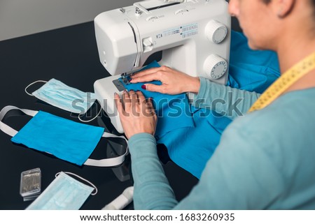 Hands sewing fabric with machine to make homemade surgical masks due to lack of material during covid-19 coronavirus crisis. Royalty-Free Stock Photo #1683260935