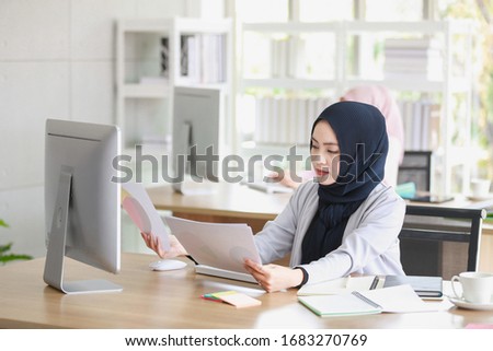 beautiful Muslim woman was sitting intently at the computer screen in the office with another colleague.