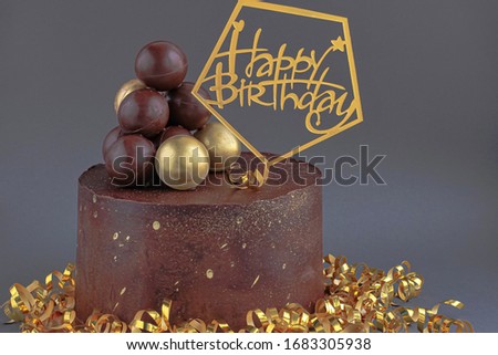Chocolate birthday cake with gold decorations. Holiday concept.