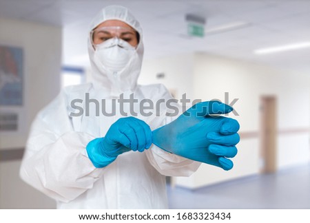 Women doctor wearing  protective suit to fight coronavirus pandemic covid-2019. Protective suit, googles, gloves, respirator. Royalty-Free Stock Photo #1683323434