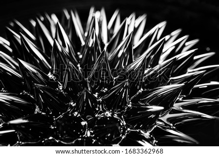 Ferrofluid, magnetic fluid close-up. Abstract minimalistic black trendy background. Fluid highly polarized in the presence of a magnetic field. Impressive, stylish iridescent black spikes.