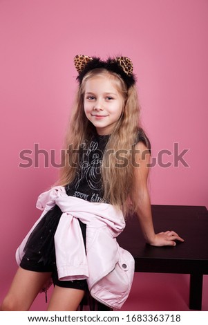 fashionable little kid in hair hoop in shape of cat ears on pink background