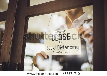 Store owner turning close sign broad through the door glass for social distancing prevent corona virus outbreak. Royalty-Free Stock Photo #1683371710